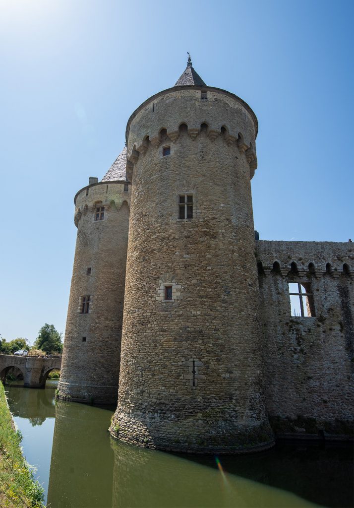 The round tower of a French castle surrounded by a moat
